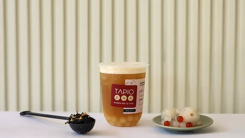 A Tapiocha milk tea with a scoop of tapioca pearls on a fluted counter