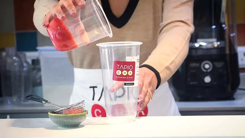 A Tapiocha barista preparing a strawberry drink at the counter
